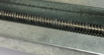 Close-up view of a screw drive mechanism within a garage door guide, demonstrating the mechanical parts used in garage door operations.